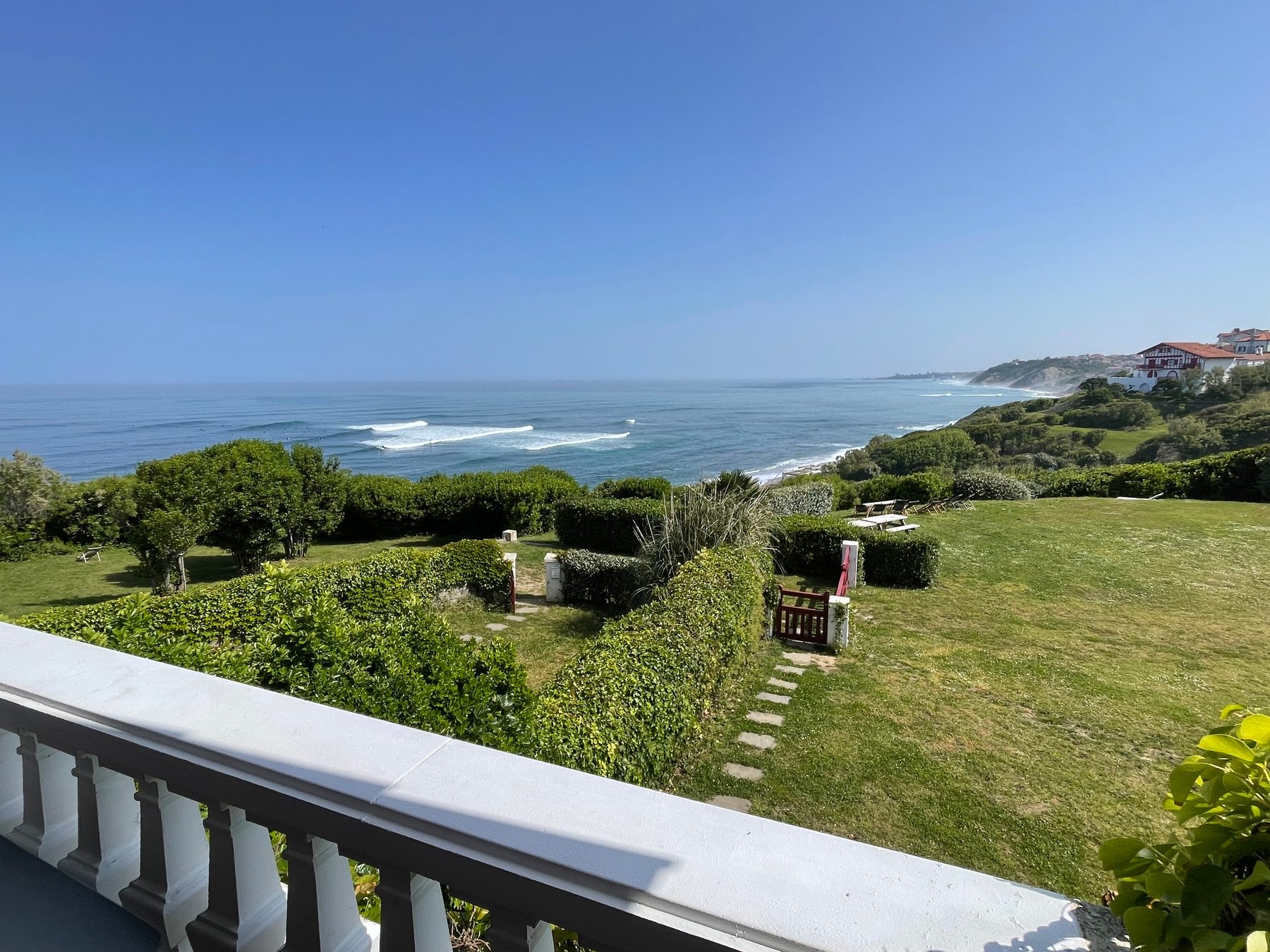 Balcon à balustrade blanche de l'Appartement 4 avec vue sur la pelouse, l'océan et la côte
