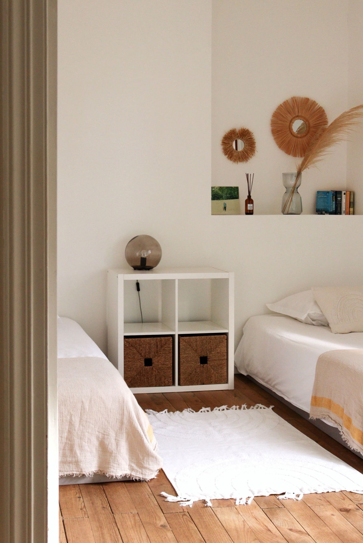 Chambre lumineuse à deux lits simples, étagère blanche à paniers et miroirs en raphia, Appartement 4