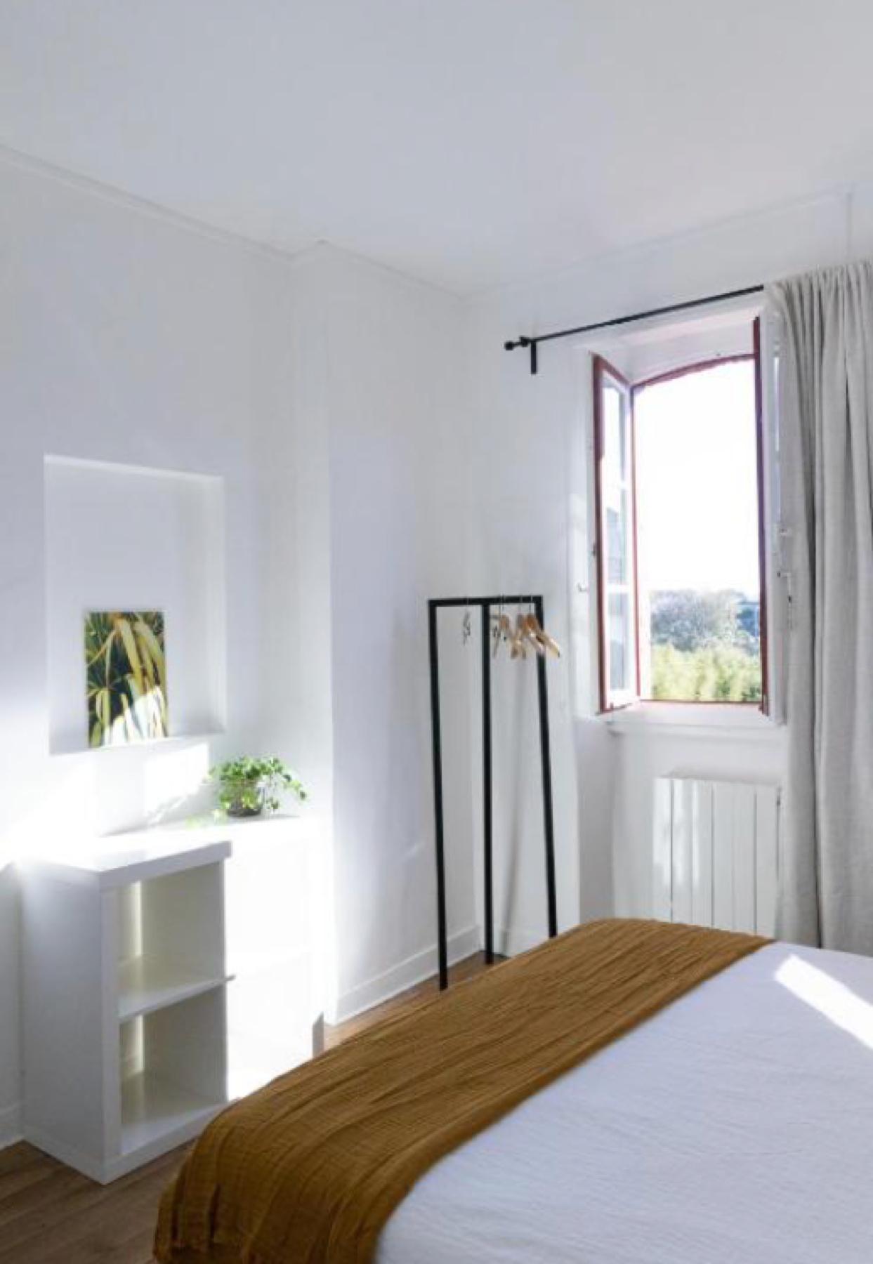 Chambre blanche lumineuse avec lit, plaid moutarde, portant à vêtements et fenêtre ouverte, Appartement 4