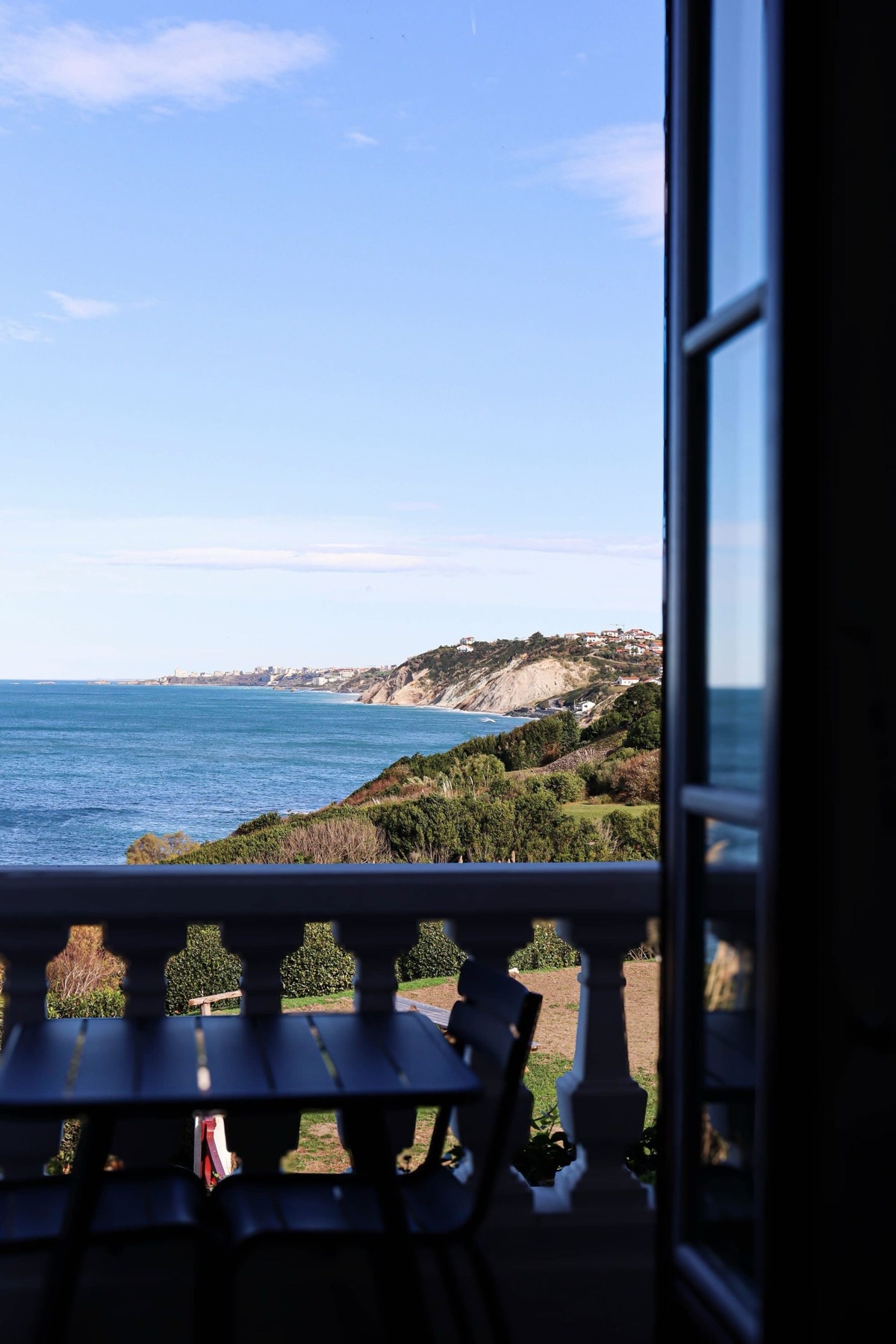 Balcon de l'Appartement 4 avec table et chaises, vue sur l'océan et les falaises de la côte